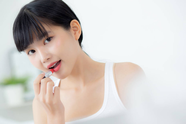 Mooie jonge aziatische vrouw van toepassing lippenstift rood op de mond, schoonheid meisje op zoek naar gezicht bij spiegel voor make-up cosmetische met lippen elegantie, make-up met sexy van vrouwelijke, huidverzorging en gezondheid concept. - Foto, afbeelding