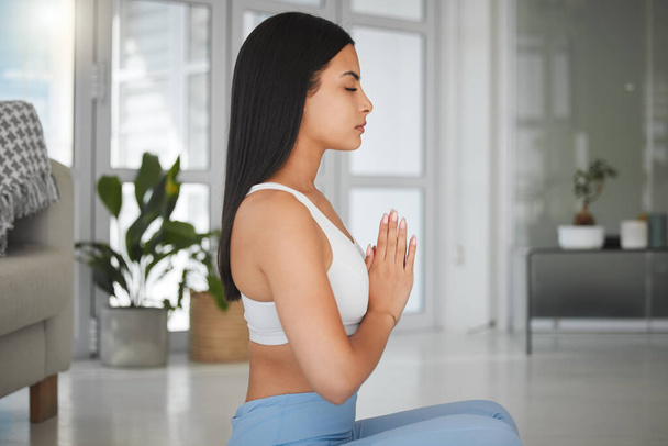 Tiro de una joven deportista meditando mientras practica yoga en casa. - Foto, imagen