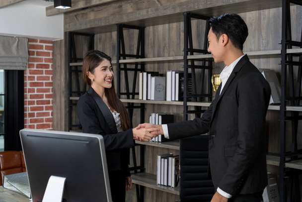 attractive businesswoman standing and shaking hand with businessman partner with smile in office room. satisficed collaboration business. success contract agreement.  - Fotoğraf, Görsel
