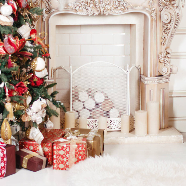 This photo depicts image of Beautiful Christmas gift boxes on floor near fir tree in room - Foto, Imagem