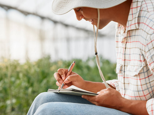 Фотография молодого человека, пишущего заметки во время работы в теплице на ферме. - Фото, изображение