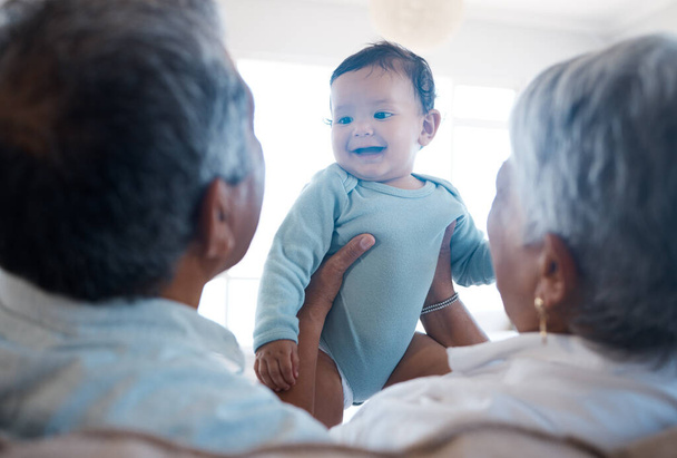 Shot of grandparents bonding with their grandchild on a sofa at home. - 写真・画像