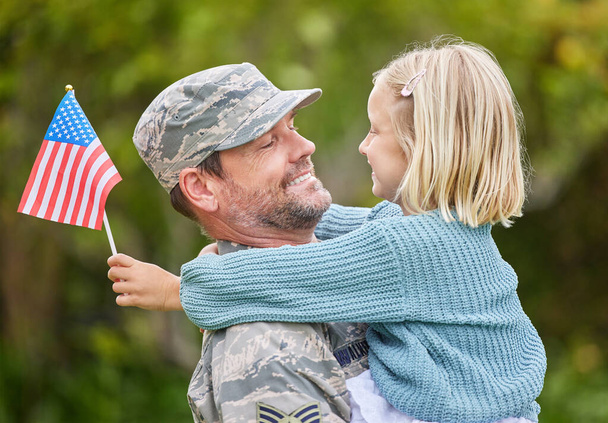 Shot of a father returning from the army hugging his daughter outside. - Foto, imagen