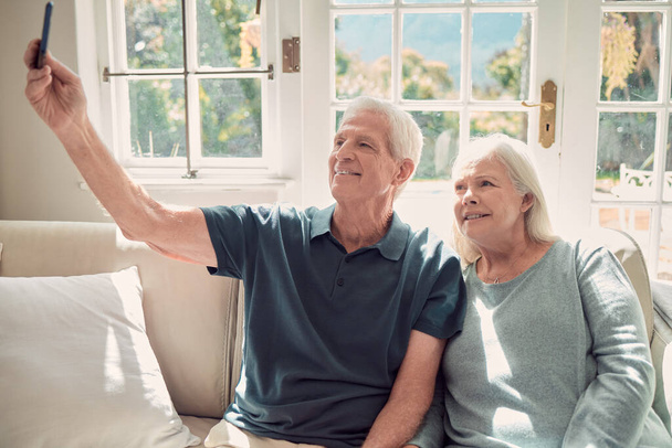Cropped shot of an affectionate senior couple sitting in their living room at home. - 写真・画像