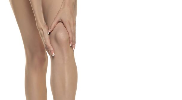 жінка тримає своє болюче коліно на білому студійному фоні
. - Фото, зображення
