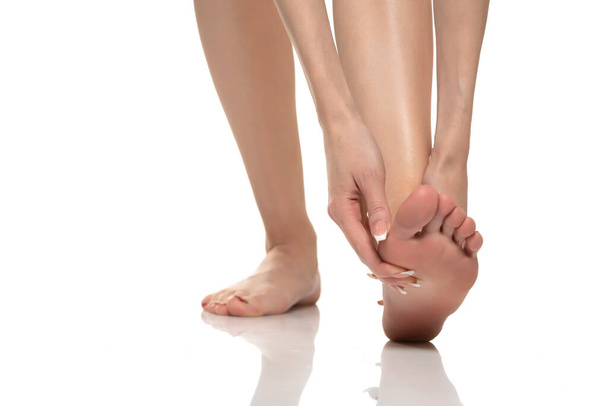 Боль в ногах у женщин на белом фоне студии. Концепция боли - Фото, изображение