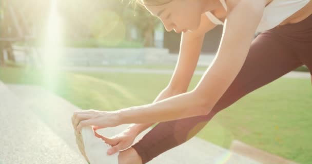 Belle jeune femme athlète asiatique exercices étirant son corps échauffer après avoir couru dans l'environnement du parc urbain au coucher du soleil du soir. Exercice extérieur et fitness concept de mode de vie sain. - Séquence, vidéo