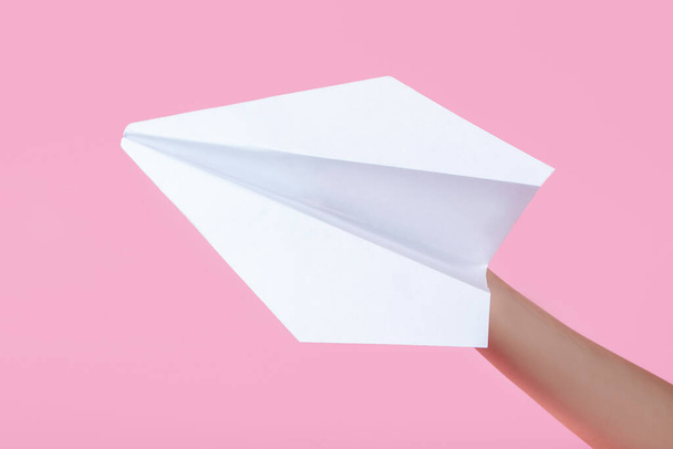 paper plane in the children's hand on a pink background. travel games with baby. concept of flying into the future. games without a smartphone. origami paper work. games at school - Valokuva, kuva