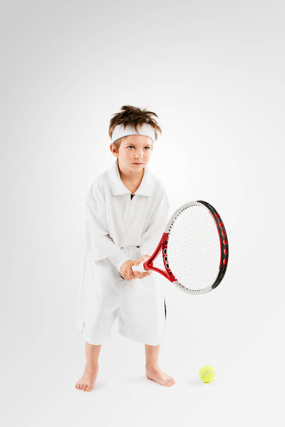 Studio shot of an adorable little boy dressing up as a tennis player. - Foto, afbeelding