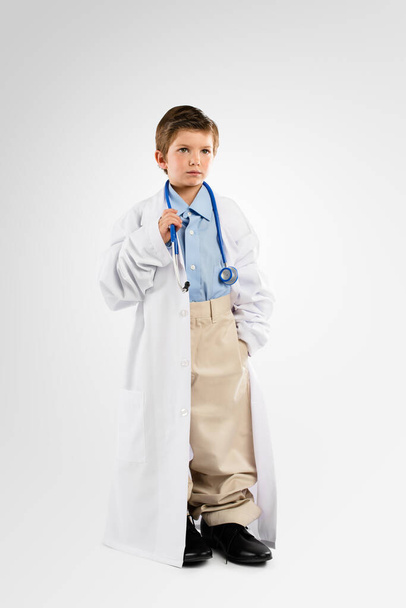Студийный снимок очаровательного маленького мальчика, одетого как врач. - Фото, изображение