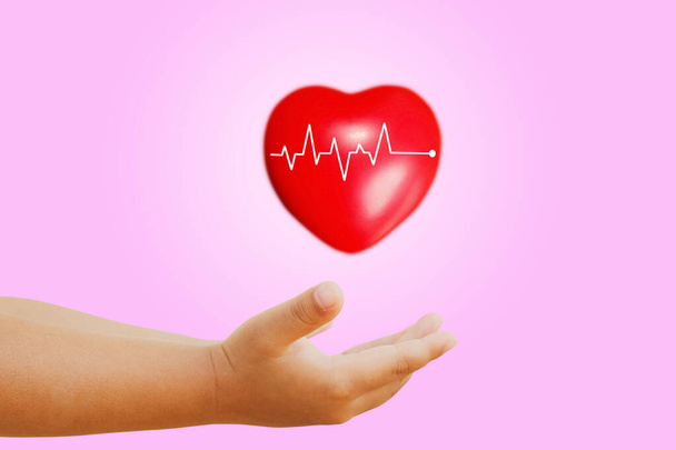 Carino bambino lanciando palla simbolo del cuore con frequenza cardiaca medica: assistenza sanitaria e prevenzione del concetto di infarto acuto. - Foto, immagini