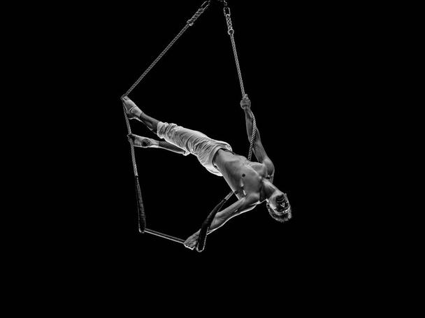 Muscular male air circus artist performances with dance trapeze. - Foto, afbeelding