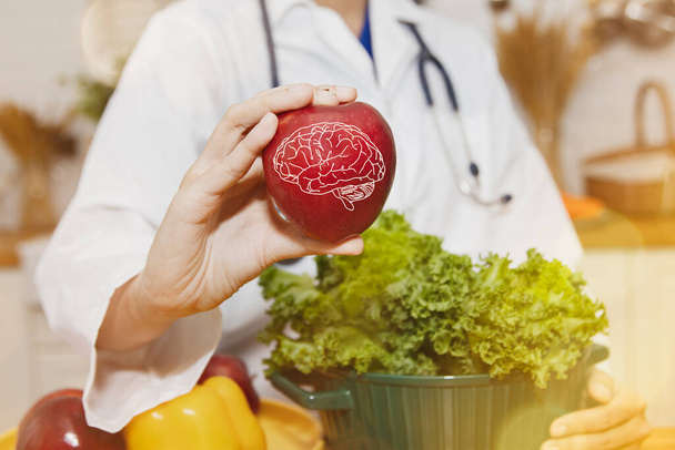 Női táplálkozási orvos azt mutatja, vörös alma gyümölcs van az agy tápláló előnyeit, gátolja a Parkinson-kór, növeli és táplálkozási egészségügyi ellátások: Egészségügyi és táplálkozási koncepció. - Fotó, kép