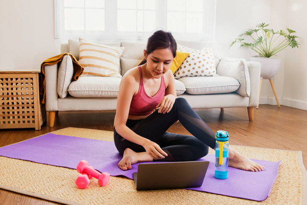 Young asian woman lifestyle exercises living room study at home with exciting interest in researching the right way to lose weight : Happy women prepare dumbbells and yoga mats for healthy sports. - 写真・画像
