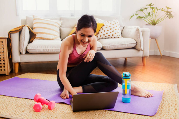 Cute Asian woman exercises  living room study at home with exciting interest in researching the right way to lose weight : Happy women prepare dumbbells and yoga mats for healthy sports. - Photo, Image