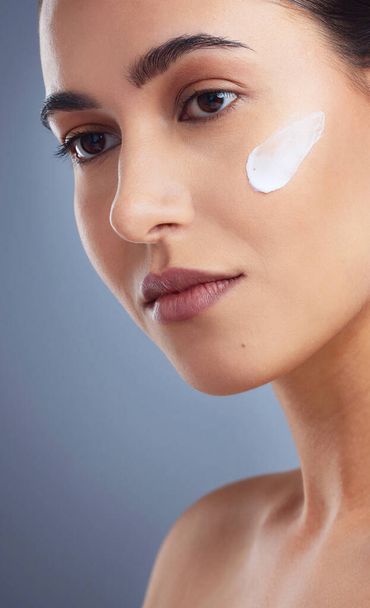 Studio shot of a beautiful woman posing with moisturiser on her face. - Photo, Image