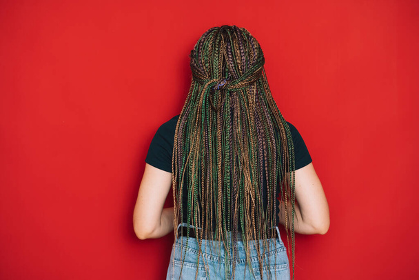 Girl with multi-colored pigtails facing a red background. - Foto, imagen