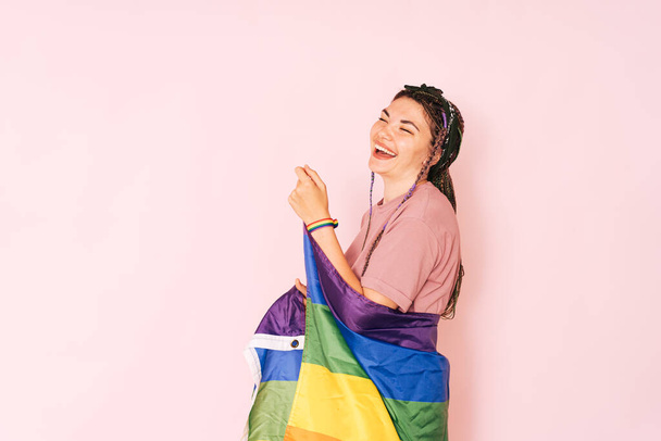 Laughing girl with rainbow flag against pink background. - Zdjęcie, obraz