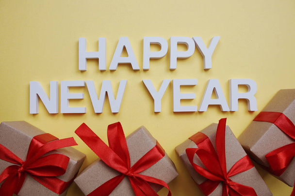 Happy New Year alphabet letters with gift boxes on yellow background - Foto, imagen