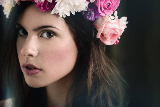 Portrait of a beautiful young woman wearing a floral head wreath. - 写真・画像
