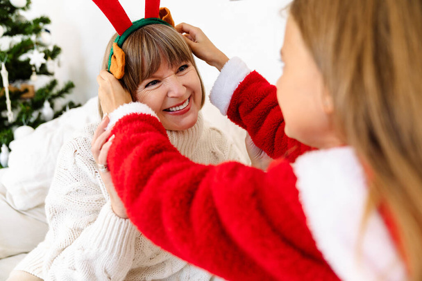 White family making fun with Christmas reindeer antlers headband at home - Photo, Image
