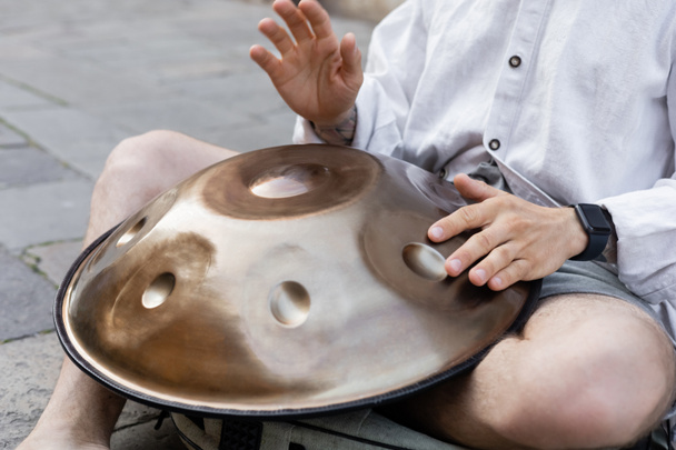 Cropped view of street musician performing hang drum on urban street  - Fotó, kép