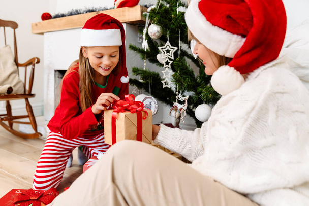 White family giving presents to each other by Christmas tree at home - Φωτογραφία, εικόνα