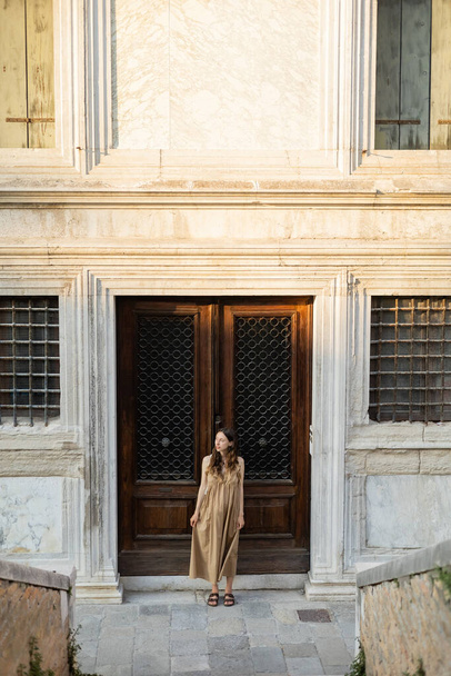 Pregnant woman in dress looking away near building on street in Venice  - 写真・画像