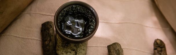 Top view of bowl with tea on stone on blanket outdoors, banner  - 写真・画像