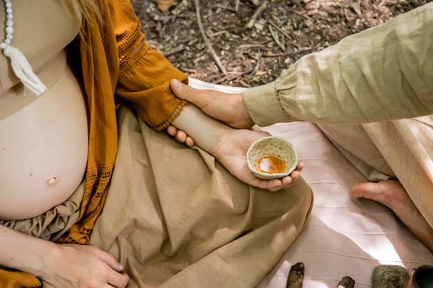 Vágott kilátás férfi megható kéz a terhes feleség kezében teáscsésze az erdőben  - Fotó, kép