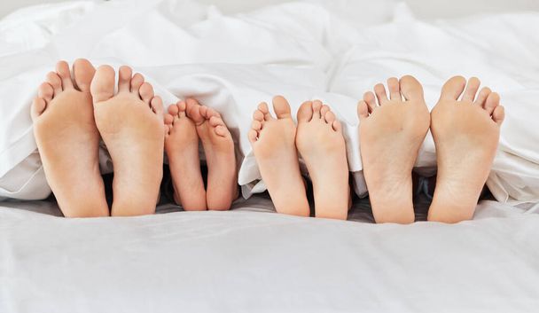 Tourné d'une famille posant pieds nus sur un lit à la maison. - Photo, image