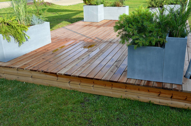 It is a heartwood that has a yellowish-brown to greenish appearance when fresh. separate wooden terrace on the lawn with fiberglass, plastic flower pots - Foto, Imagen