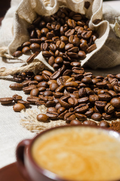 Uma xícara de café em um fundo de café e grãos moídos na serapilheira. Arabica é o tipo mais comum de café. - Foto, Imagem