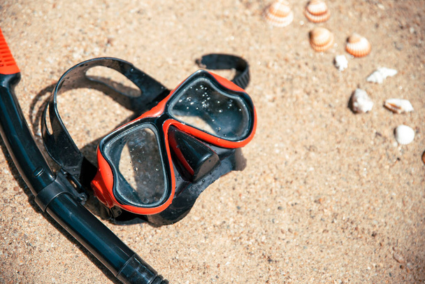 Červená půlka potápěčské masky na pláži písku, zblízka. Rekreační sportovní koníček. Šnorchlování a potápění koncept.  - Fotografie, Obrázek