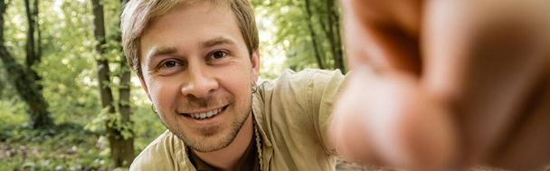 Smiling man looking at camera in summer forest, banner  - Фото, зображення