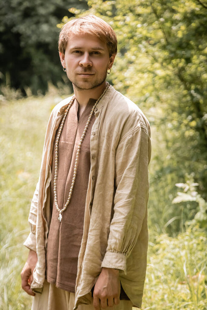 Portrait of man in linen shirt standing in forest  - Foto, Imagen