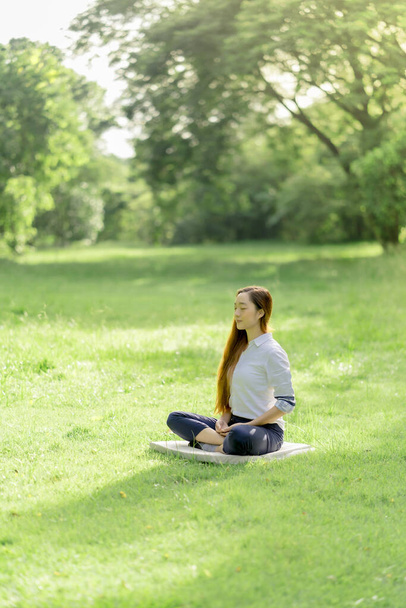 Medytacja na świeżym powietrzu. Szczęśliwa kobieta medytująca i relaksująca się w parku. Medytacja w naturze. Pojęcie zdrowego stylu życia i relaksu. Piękna kobieta praktykująca medytację na trawie - Zdjęcie, obraz