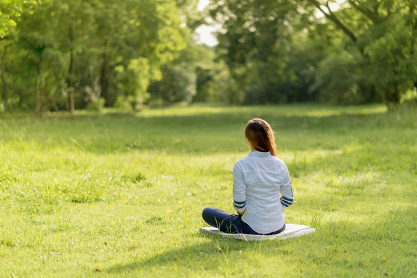 Achterzijde van aziatische vrouw die mediteert in het park. Gooide geluk van innerlijke vrede. - Foto, afbeelding