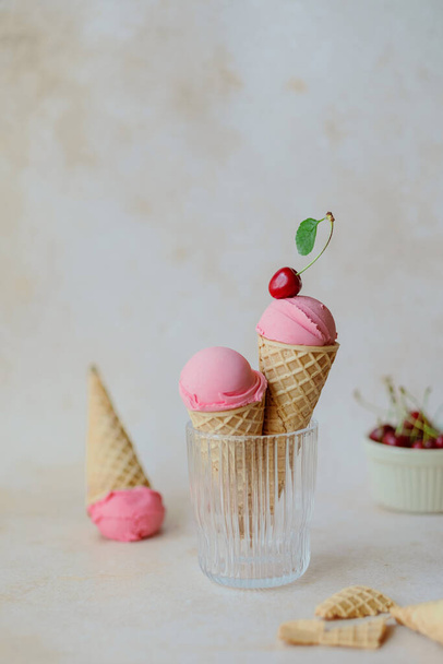 Creamy vegan cherries ice cream in the horn in a glass, styling cherry. Waffle cone horn upside down. Summer seasonal cold sweet healthy vegan dessert. High quality photo - Foto, Imagem
