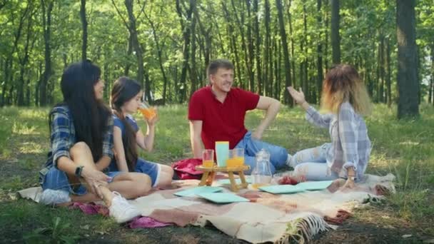 fröhliche Gesellschaft, Mama, Papa, Sohn, Tochter und ihre Freunde picknicken im Waldgebiet. Familiencamping im Sommer.Ausruhen mit Zelt im Wald Stadtpark - Filmmaterial, Video
