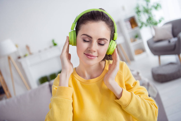Photo of peaceful adorable girl closed eyes hands touch headphones enjoy new single house indoors. - Foto, Imagen