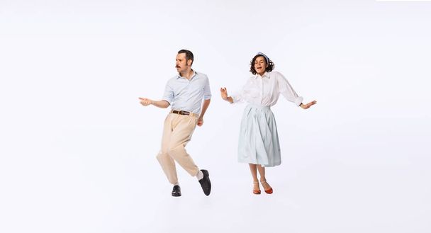 Portrait of young beautiful couple, man and woman, dancing retro dance isolated over white studio background. Concept of vintage fashion, hobby, activity, art, music, party, creativity and ad - Photo, Image