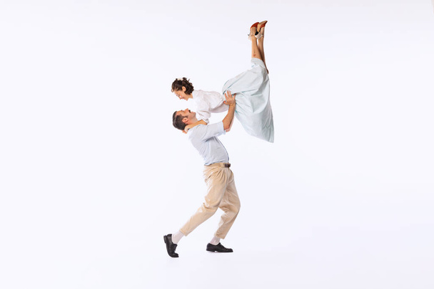 Portrait of young beautiful couple, man and woman, dancing isolated over white studio background. Dance lift. Concept of vintage fashion, hobby, activity, art, music, party, creativity and ad - Foto, Imagem