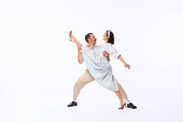 Portrait of young beautiful couple, man and woman, dancing isolated over white studio background. Twine. Concept of vintage fashion, hobby, activity, art, music, party, creativity and ad - Photo, Image