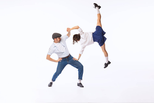 Portrait of cheerful couple, man and woman, dancing boogie woogie isolated over white studio background. Concept of vintage fashion, hobby, activity, art, music, party, creativity and ad - Photo, image