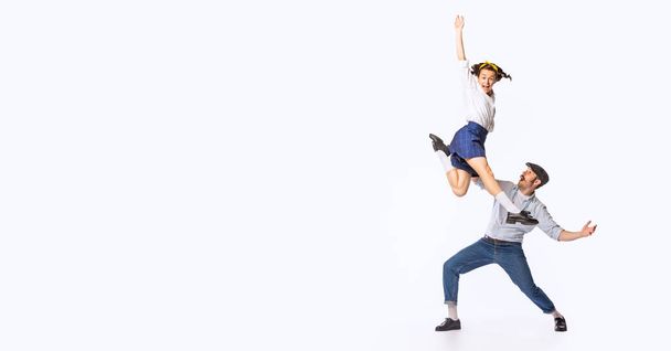 Portret van een mooi koppel, man en vrouw, dansende swing, rock of lindy hop geïsoleerd over witte studio achtergrond. Concept van vintage mode, hobby, activiteit, kunst, muziek, feest, creativiteit en reclame - Foto, afbeelding