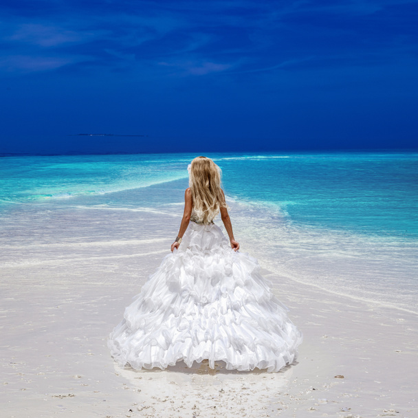 Panna młoda na plaży. Stylowy model żeński w eleganckiej sukni na plaży Malediwy. Elegancja. Panna młoda na Malediwach. Moda ślubna. Elegancka kobieta w niesamowitej białej sukience. Podróże luksusowe - Zdjęcie, obraz
