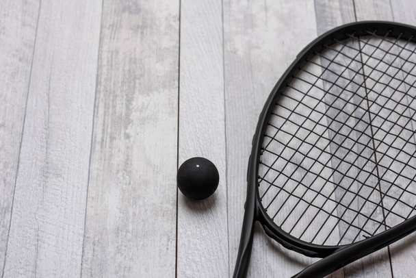 Black squash racket and ball on grey court. Horizontal sport theme poster, greeting cards, headers, website and app - Photo, Image