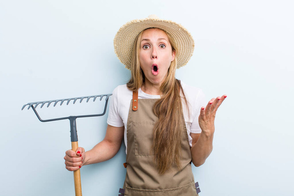 young adult blonde woman. farmer with a rake - Foto, Imagen
