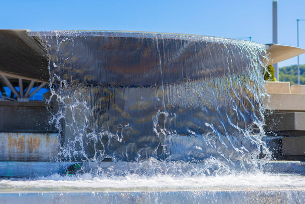 Una corriente de agua clara que vierte desde un tazón grande. Fuente de la calle en cascada que decora la ciudad - Foto, imagen